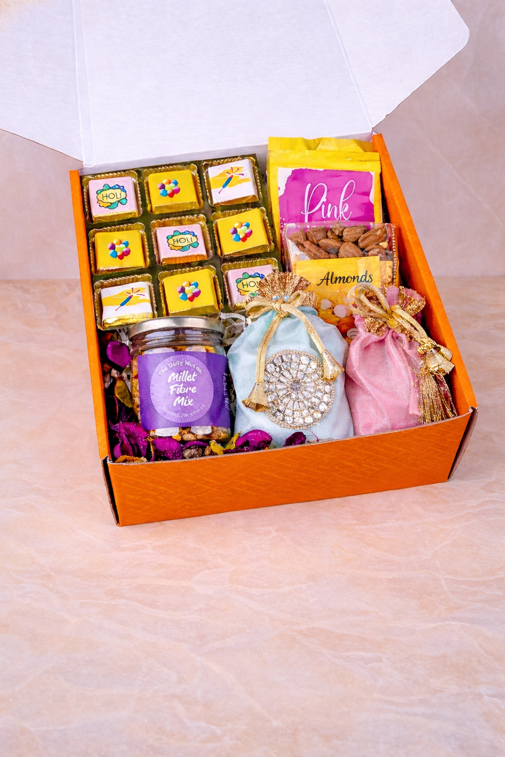 Luxury Raksha Bandhan gift hamper with designer rakhi, chocolates, dry fruits, sweets, and festive gift items arranged in an orange gift box.