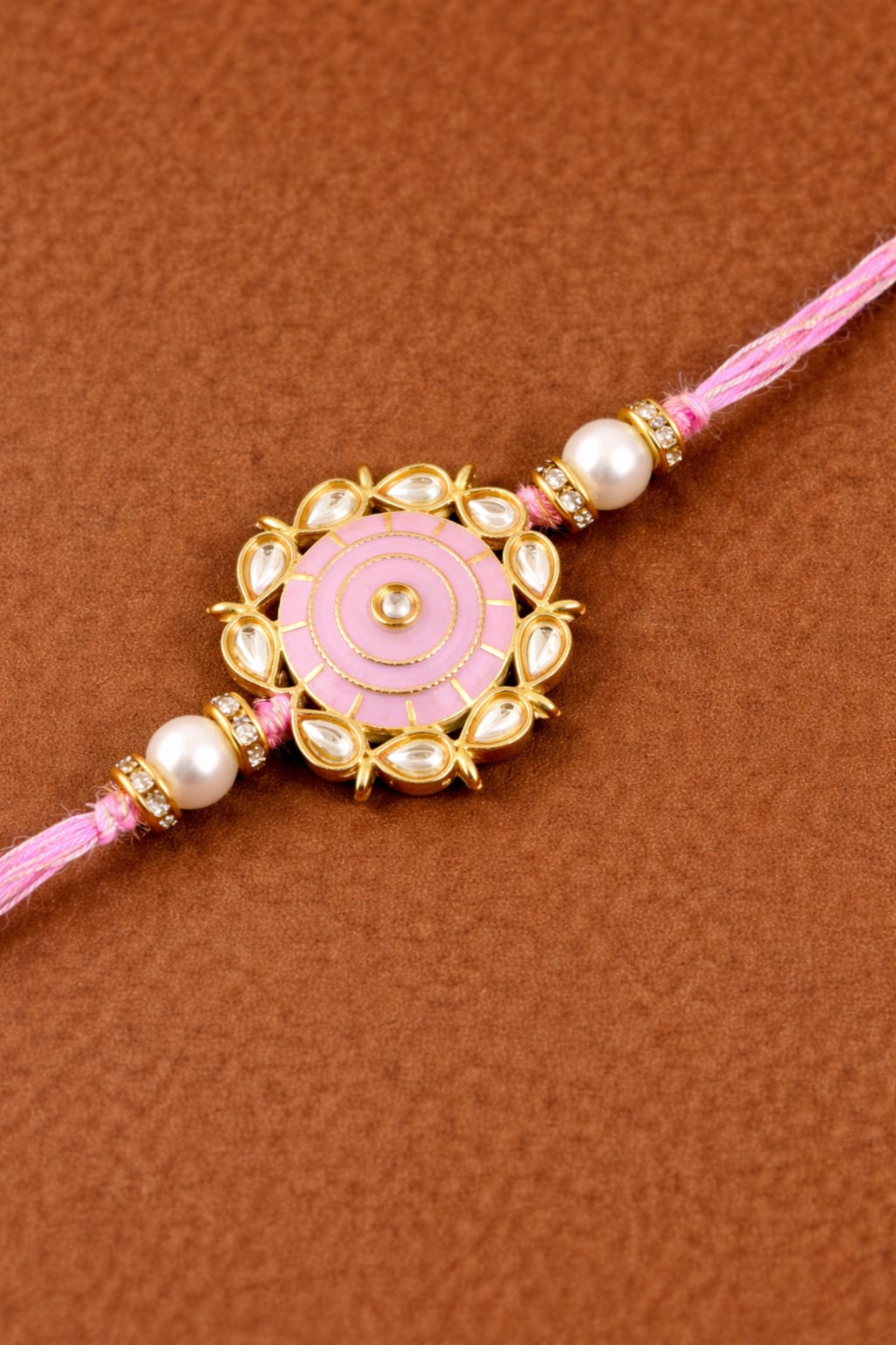 Elegant green rakhi with gold floral medallion, pearl beads, and stone detailing on braided green thread.