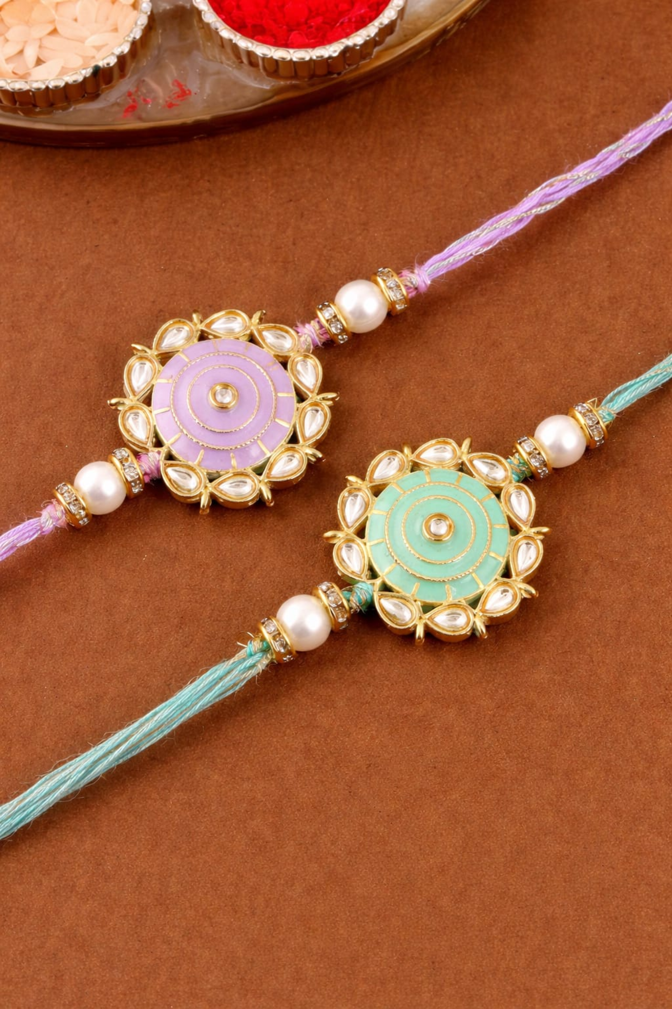 Elegant green rakhi with gold floral medallion, pearl beads, and stone detailing on braided green thread.