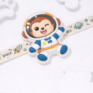Cute astronaut cartoon kids rakhi with space-themed strap featuring rockets and planets.